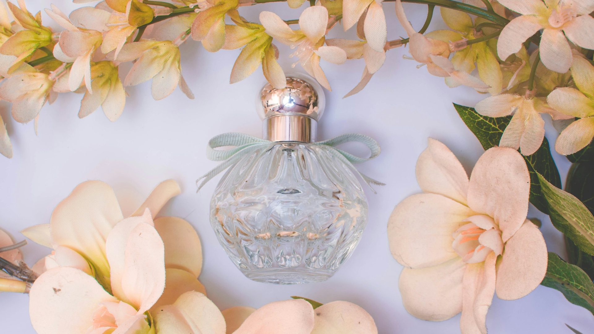 Flacone di profumo in vetro tra fiori chiari